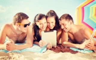 group of smiling people with tablet pc on beach